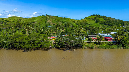 Aerial shot captures local life as they swim and play in the brown water of the Sigatoka River,...