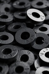 Close-up of black metal washers arranged in a disorganized pile showcasing various sizes and textures in industrial setting