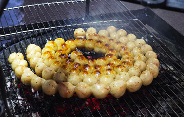Traditional Thai Isaan sausages (sai krok Isaan) being grilled over hot charcoal, a popular street food snack in northeastern Thailand 