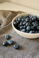 Fresh blueberries in the bowl on the kitchen table close up