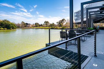 Modern terrace with pergola structure and outdoor dining tables and chairs overlooking the lake....