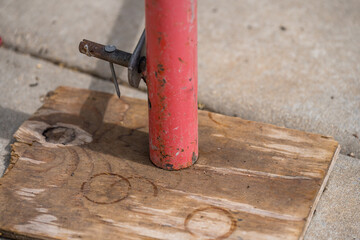 Support post anchored to wooden base on pavement for construction project in urban area during...
