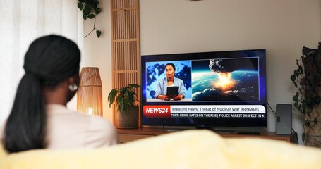 Breaking news, nuclear war and woman watching tv on sofa for live report, global conflict or threat. Screen, back of person or television broadcast of military attack with explosion headlines in home