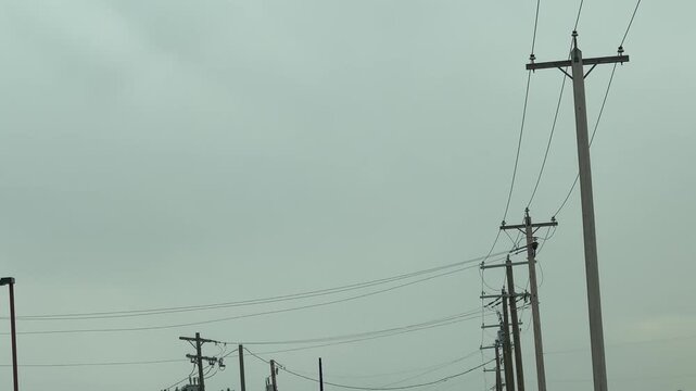 Overcast sky behind wooden electrical power pole with high-tension lines, photographed in Canada to capture industrial energy infrastructure in minimal weather conditions.