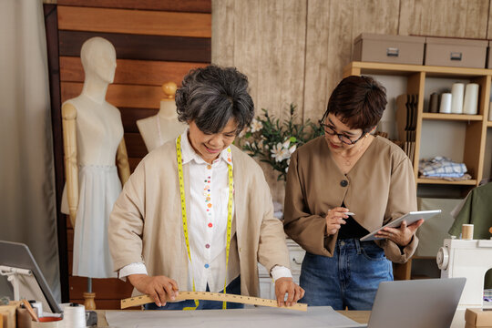 two Asian women working together in a clothing design studio.