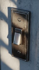 Close-Up Image of a Vintage Light Switch Plate with Sunlit Shadows on a Textured Wall Surface