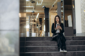 Fototapeta premium Woman Sitting Indoor While Using Her Smartphone in Modern Interior