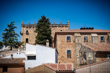 Fototapeta premium Vista panorámica del casco histórico de la ciudad española de Cáceres con vistas a los tejados de tejas marrones de edificios antiguos alrededor de la plaza principal en el soleado día de verano