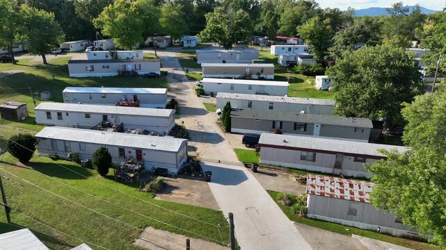 Dense populated neighborhood with mobile trailer homes in American suburb. Sunny Summer day. Aerial view. Rusty roofs of tiny buildings in cheap low income housing area of USA.