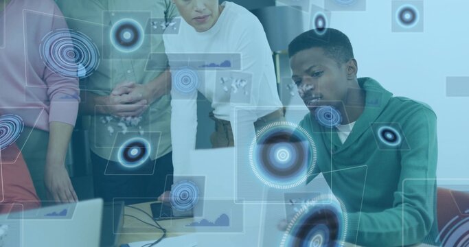 Collaborating team analyzing data around table in meeting room, using laptop and holographic charts