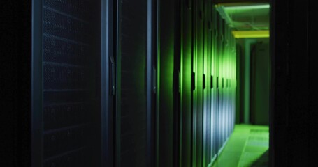 Glowing row of server racks lining data center corridor, with green LED lights and cable trays