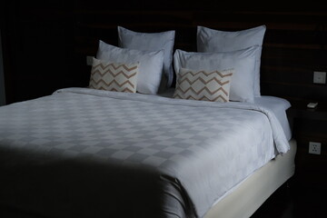 Neatly made bed with white bedding and multiple pillows