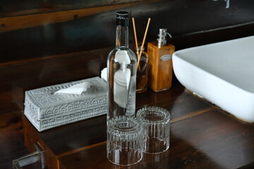 Glass bottle with water and two upside down glasses on wooden washstand