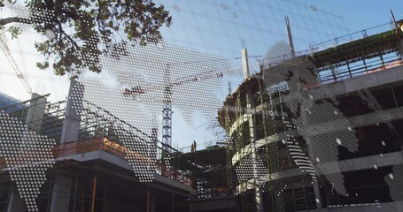 Standing worker wearing hard hat and hi-vis vest inspecting columns at building site with crane