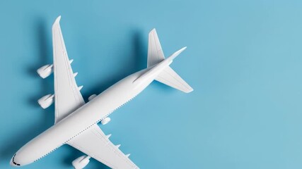 A white airplane model is positioned diagonally on a vibrant blue background, viewed from directly above
