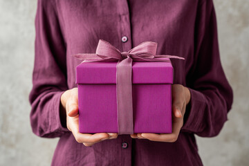 woman in dress holding purple gift box
