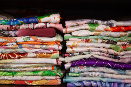 Colorful stacks of neatly folded Japanese Kimono fabric showcasing intricate patterns and vibrant designs, perfect for depicting traditional textile arts, creativity, and style.