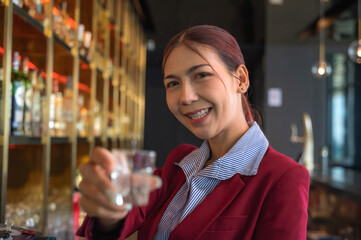 Asian bartender woman holding shot glass  working behind counter bar