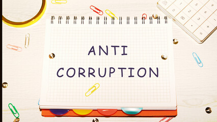 Anti corruption text written on a notebook in a cage on the table