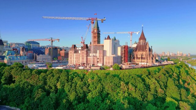 Ottawa, ON, Canada. July 05, 2025: Canada Parliament Hill during early morning with cranes visible on the horizon, highlighting ongoing construction against a clear blue sky