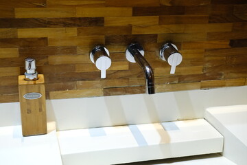 Chrome faucet with mixers mounted in wooden wall