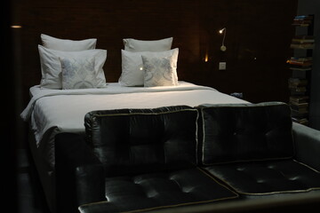 Neatly made bed with white bedding in soft night light