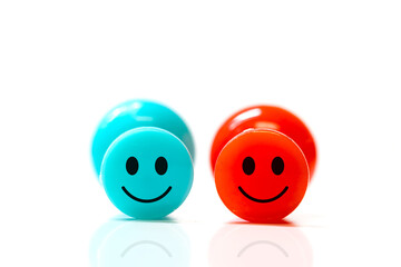 Two plastic push pins with smiley faces on white background.
