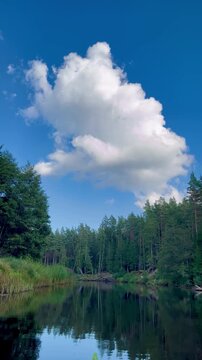 Cloud towering above the Irbe river in Latvia as calm reflective water mirrors forested banks, capturing quiet wilderness, open sky and a gentle sense of natural freedom