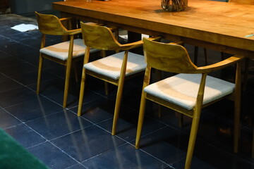 Stylish Wooden Chairs with Cushions at Large Wooden Table in Warm Lamp Light