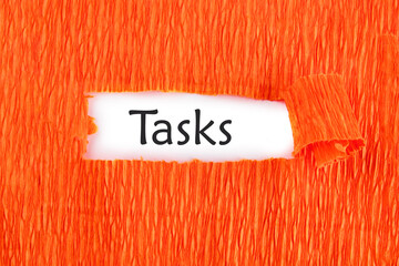 Business concept. TASKS - word on a white sheet under an orange background