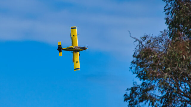 Yellow crop duster banking sharply in clear sky