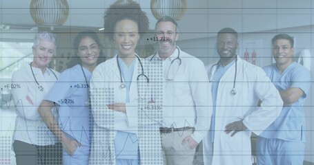 Posing medical team wearing blue scrubs and stethoscopes in clinic lobby, with overlaid line graphs