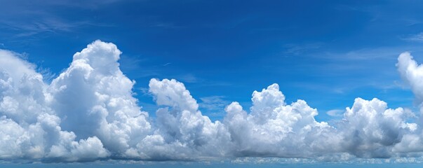Panoramic view of a vivid blue sky filled with fluffy, white cumulonimbus clouds forming a picturesque horizon against the clear backdrop