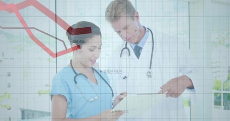 Doctor in white coat and nurse in scrubs reviewing digital tablet in clinic room, with stethoscopes