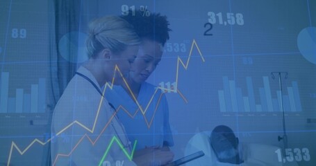 Female doctor and nurse examining tablet at bedside, with stethoscope and floating graphs