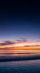 Obraz premium Tranquil ocean waves gently lap shore under a breathtaking twilight sky painted with vibrant sunset hues and distant stars emerging