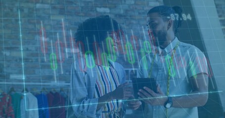 Designers consulting chart overlay on tablet in loft, with measuring tape and clothing racks