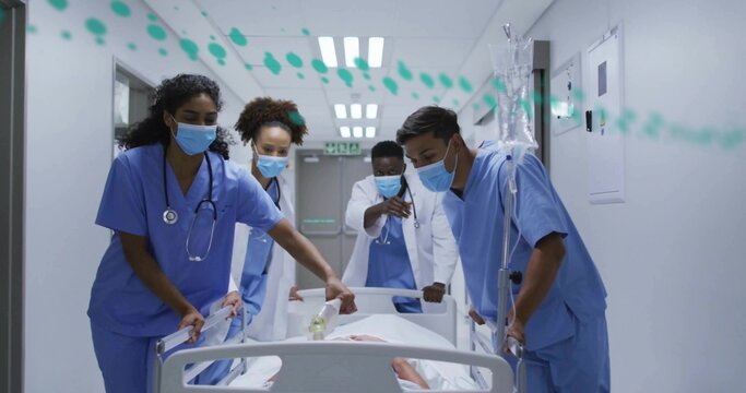 Moving masked medical team transporting patient on gurney through hospital corridor, with IV stand