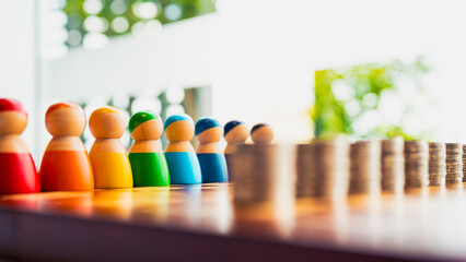 Colorful wooden figures lined up in front of coin stacks, symbolizing financial diversity, income inequality, economic distribution, budget allocation, and equal opportunity in business and society.
