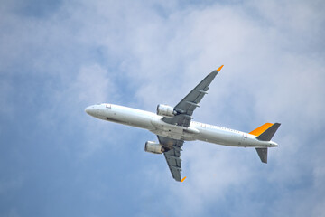 Passenger airplane flying in blue and cloudy sky. Aviation idea concept. Yellow tailed aircraft. Abroad travel. No people, nobody. Horizontal photo.