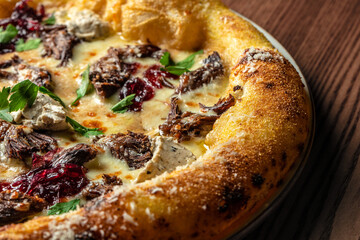 Gourmet pizza with slow-cooked beef, cream cheese, herbs, and berry sauce on a golden crust