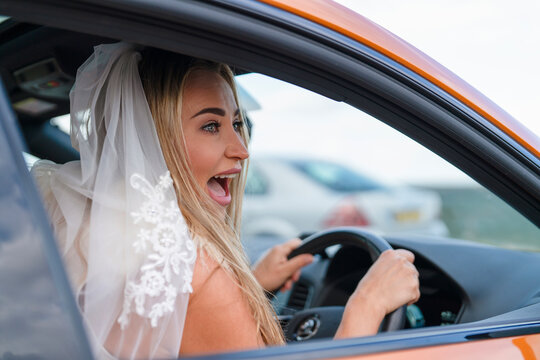 Excited bride driving a car with a joyful expression on her face during wedding festivities at a scenic location - Powered by Adobe