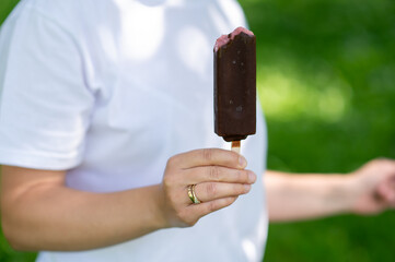 Woman holding chocolate ice cream on stick close up