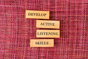Concept word Develop active listening skills on wooden blocks on a mesh background
