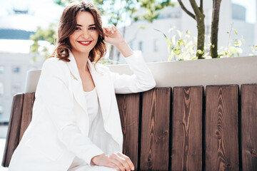 Fototapeta premium Young beautiful brunette woman wearing nice trendy white suit jacket. Sexy smiling model posing in the street at sunny day. Fashionable female outdoors. Cheerful and happy. Evening makeup, red lips