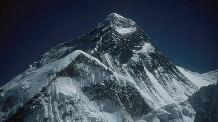 Massive snow-capped mountain peak against dark sky