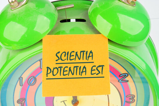 the phrase Scientia Potentia Est (Knowledge is power) written in Latin on the orange sticker on the alarm clock