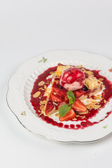 Close-up of elegant strawberry tart with ice cream scoop, almond flakes, and mint leaves on white plate, perfect for menus or advertising.