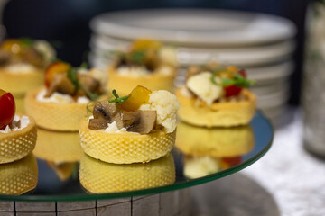 Delicate savory mini canapes in crispy pastry cups filled with mushrooms, cauliflower, cream cheese, and herbs - elegant appetizers for events, weddings, or fine dining.
