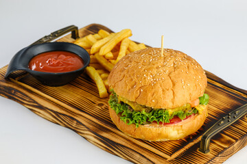 A freshly prepared cheeseburger served with crispy french fries and ketchup on a wooden serving...